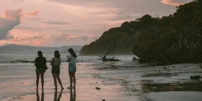 Three people on the beach at sunset in Costa Rica diving with sharks