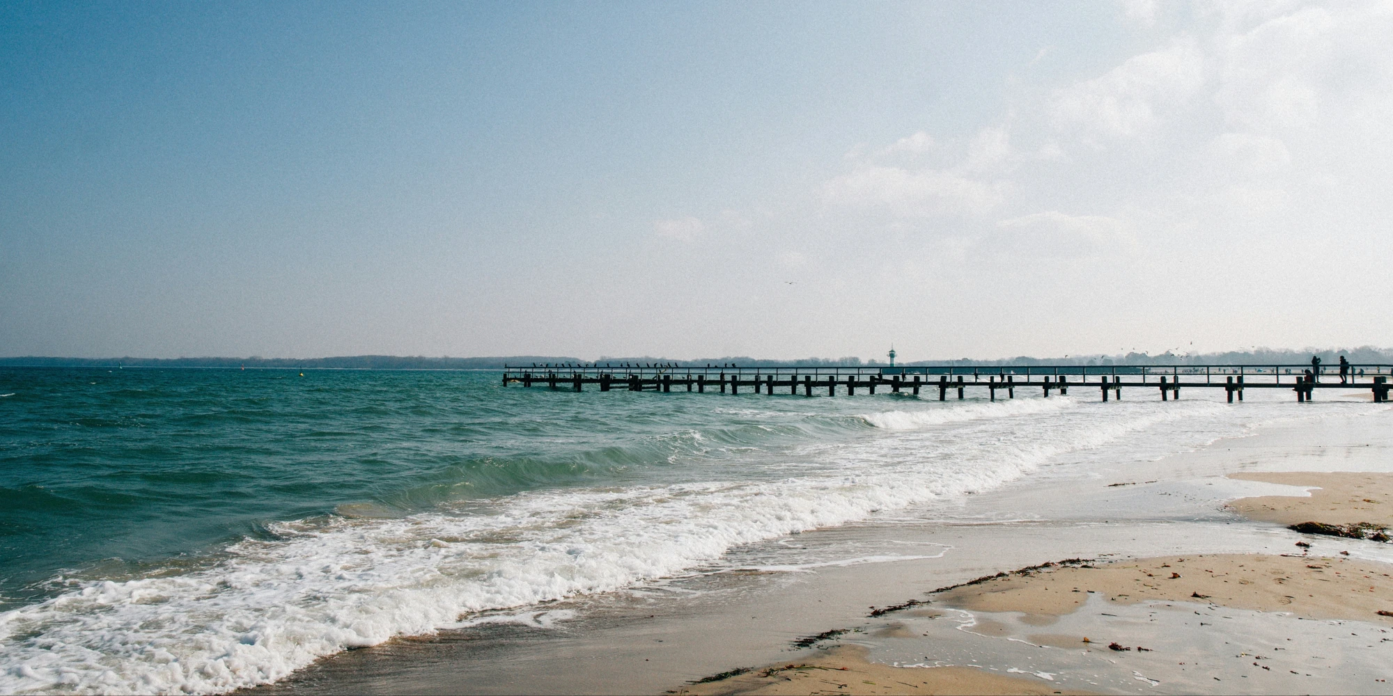 Wooden pier on the Baltic Sea beach with Travemünde in the background