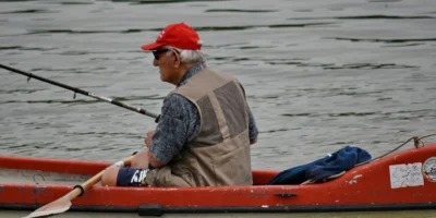 Man with a fishing rod in a red kayak on the water