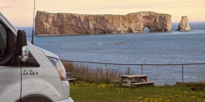 Camper van and picnic table on the coast overlooking Percé Rock in Québec