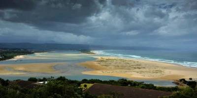 View across the lagoon, beach and ocean at Plettenberg Bay under dark storm clouds