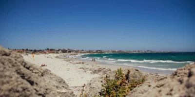 Beachgoers and waves at Sorrento Beach, with rocks in the foreground