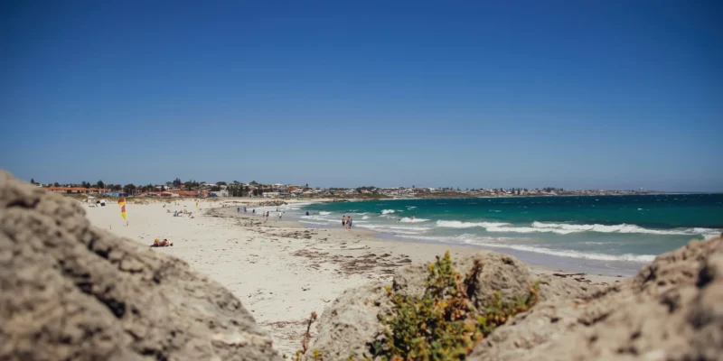Beachgoers and waves at Sorrento Beach, with rocks in the foreground