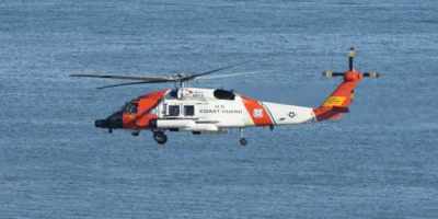 White and orange US Coast Guard helicopter flying over blue sea. Illustrative archive photo from 2021; it does not show the rescue off Ensenada in October 2026.